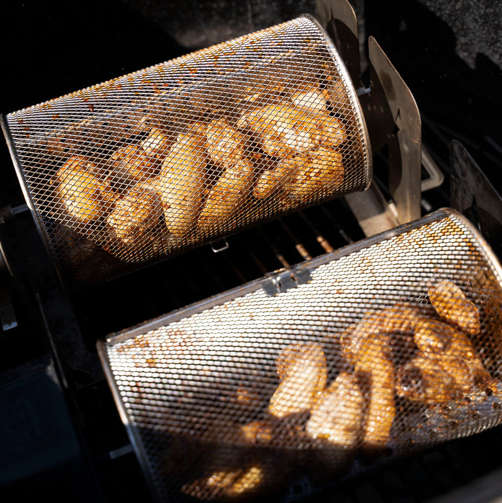 Two ROTO-Q 360 rotisserie baskets  (Round) cooking chicken wings on a grill.
