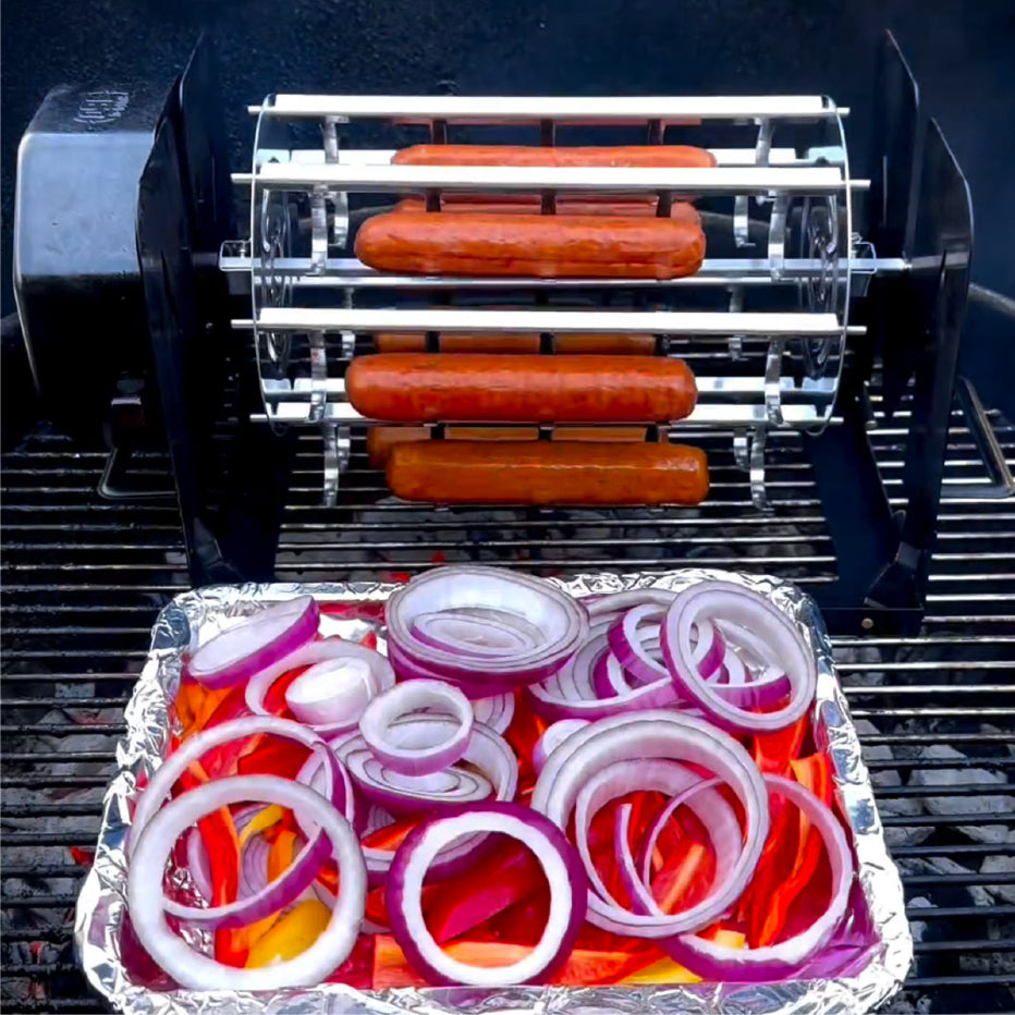 ROTO-Q 360 Sausage Rotisserie cooking sausages on a grill with a foil tray of sliced red onions and peppers.