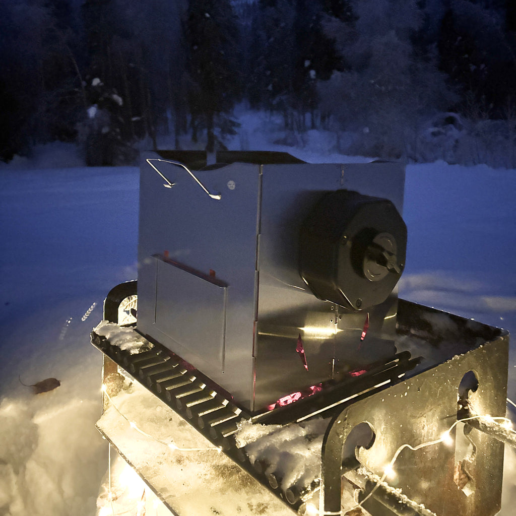 ROTO-Q 360 foldable stainless steel grill set up outdoors in the snow.