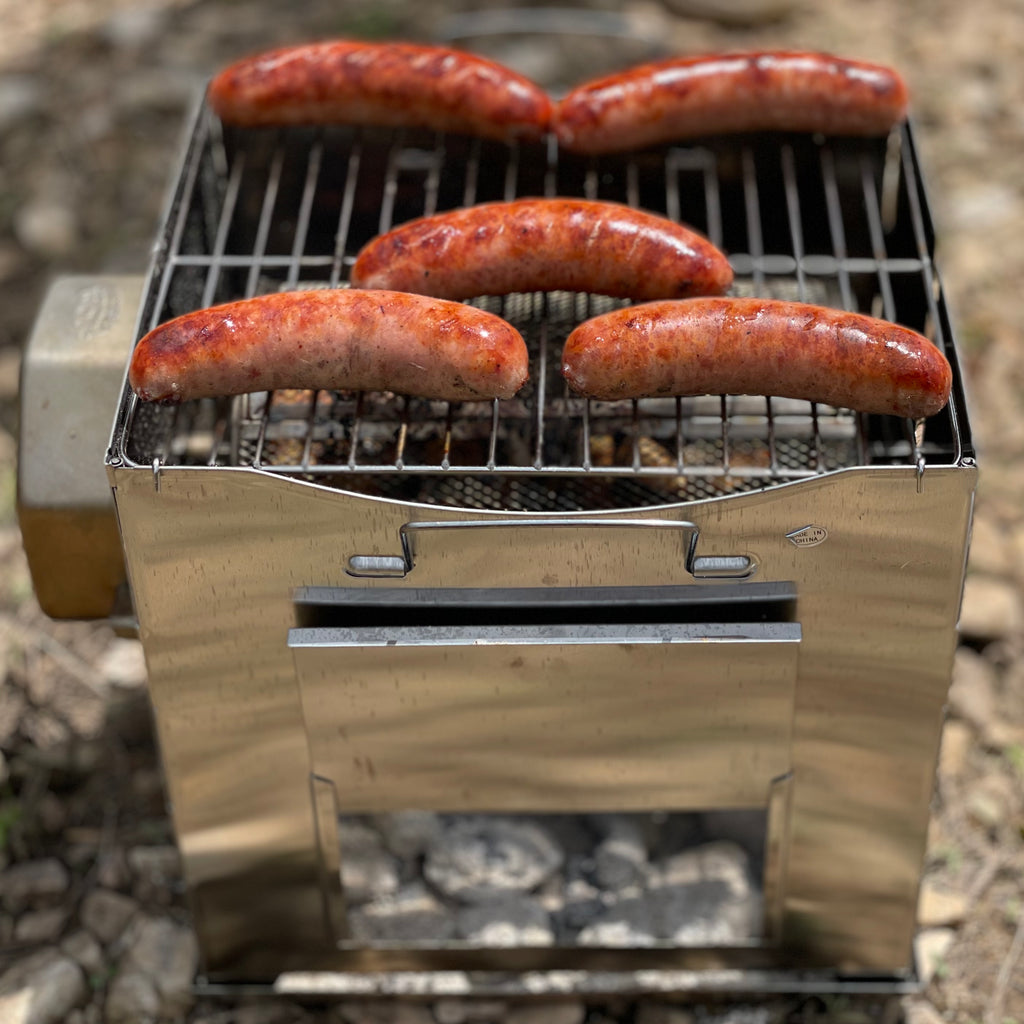 Sausages grilling on the grate of a ROTO-Q 360 Foldable Grill