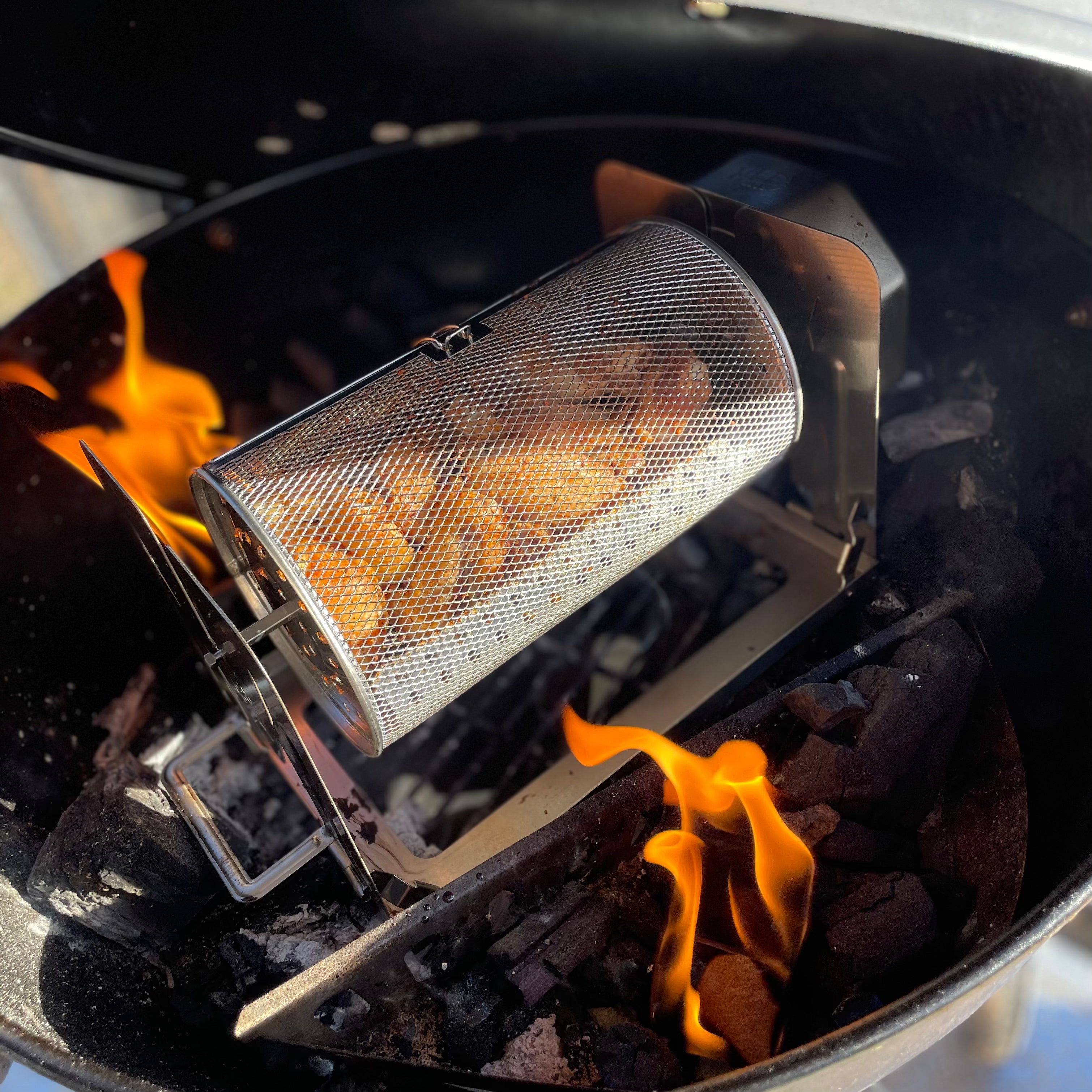 ROTO-Q 360 rotisserie basket (Round) cooking rotating potato wedges over a charcoal grill with open flames.