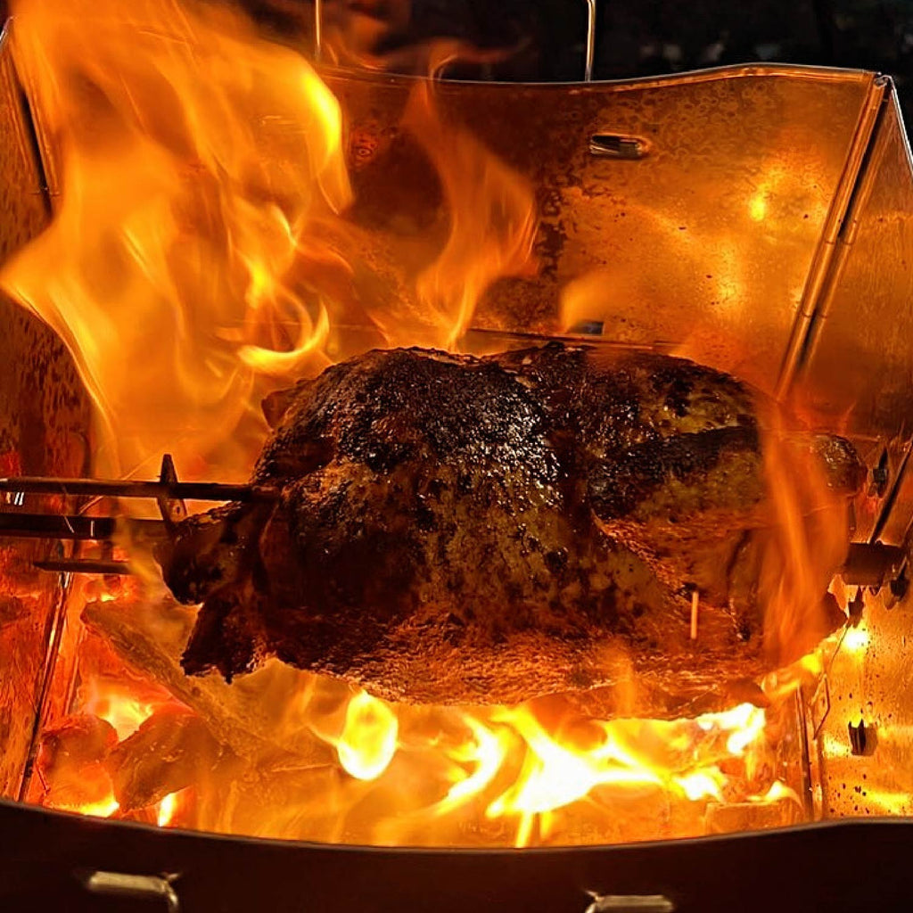 Whole chicken roasting over open flames inside a ROTO-Q 360 grill.