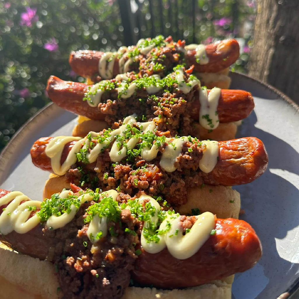 Plated chili hot dogs topped with sauce and fresh herbs
