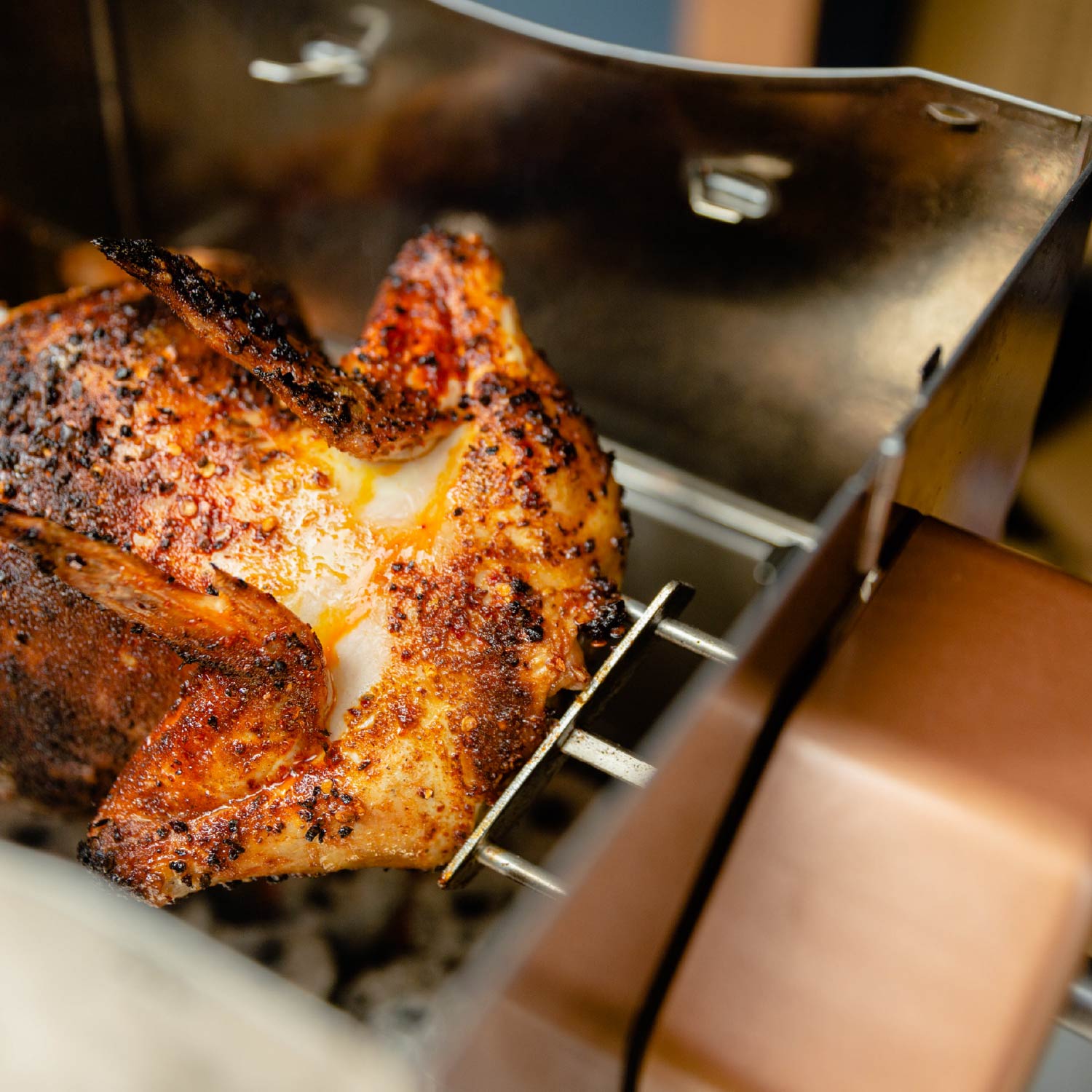 Seasoned whole chicken roasting on a rotisserie inside a ROTO-Q 360 grill.