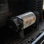 Black ROTO-Q 360 rotisserie unit with a round rotisserie basket sitting on a grill grate