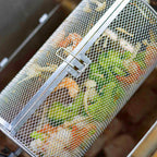 Close-up of shrimp and vegetables roasting inside a closed round rotisserie basket.